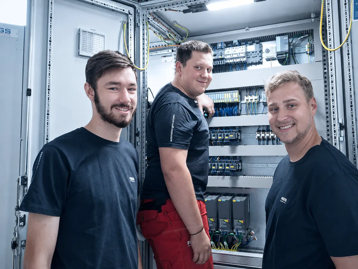 Mechatronics apprentices in front of a control cabinet