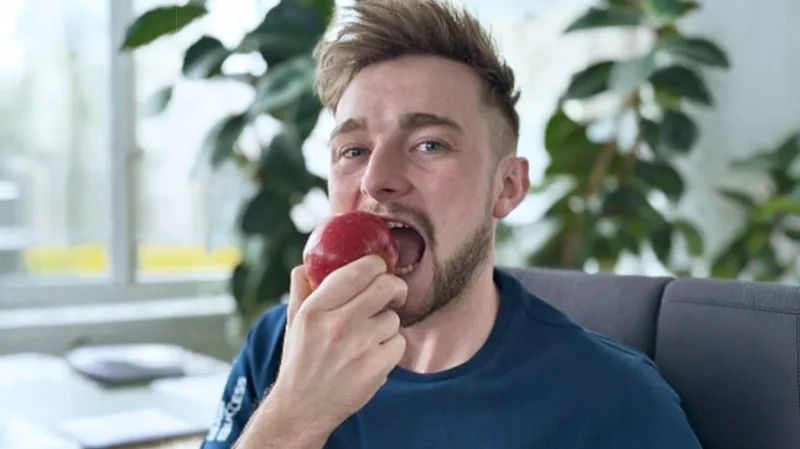 Mitarbeiter isst einen Apfel aus dem kostenlosen Obstangebot bei AGS