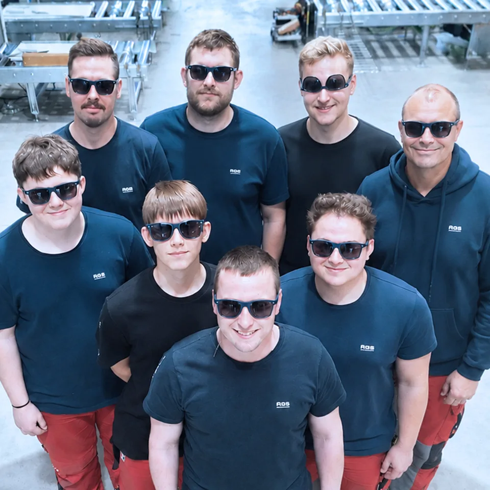 Team von AGS-Engineering mit Sonnenbrillen in der Montagehalle