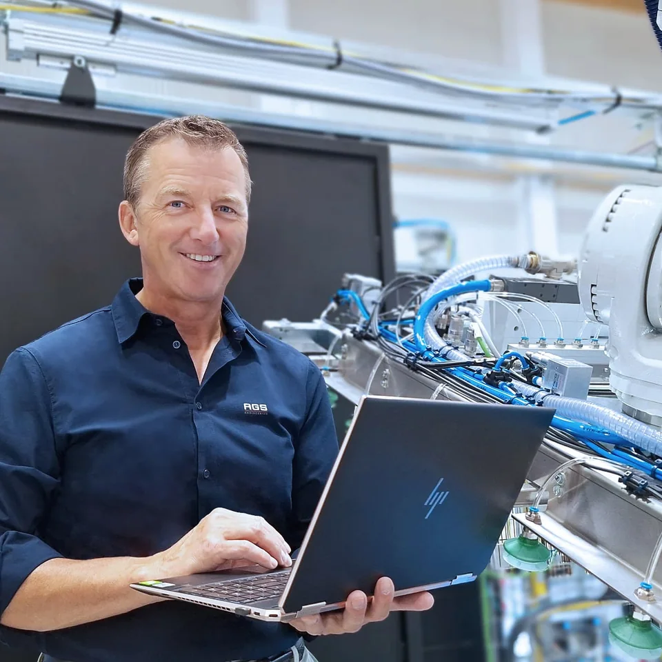 Walter Kohlbauer, founder and CEO of AGS-Engineering, with a laptop in front of a robot cell