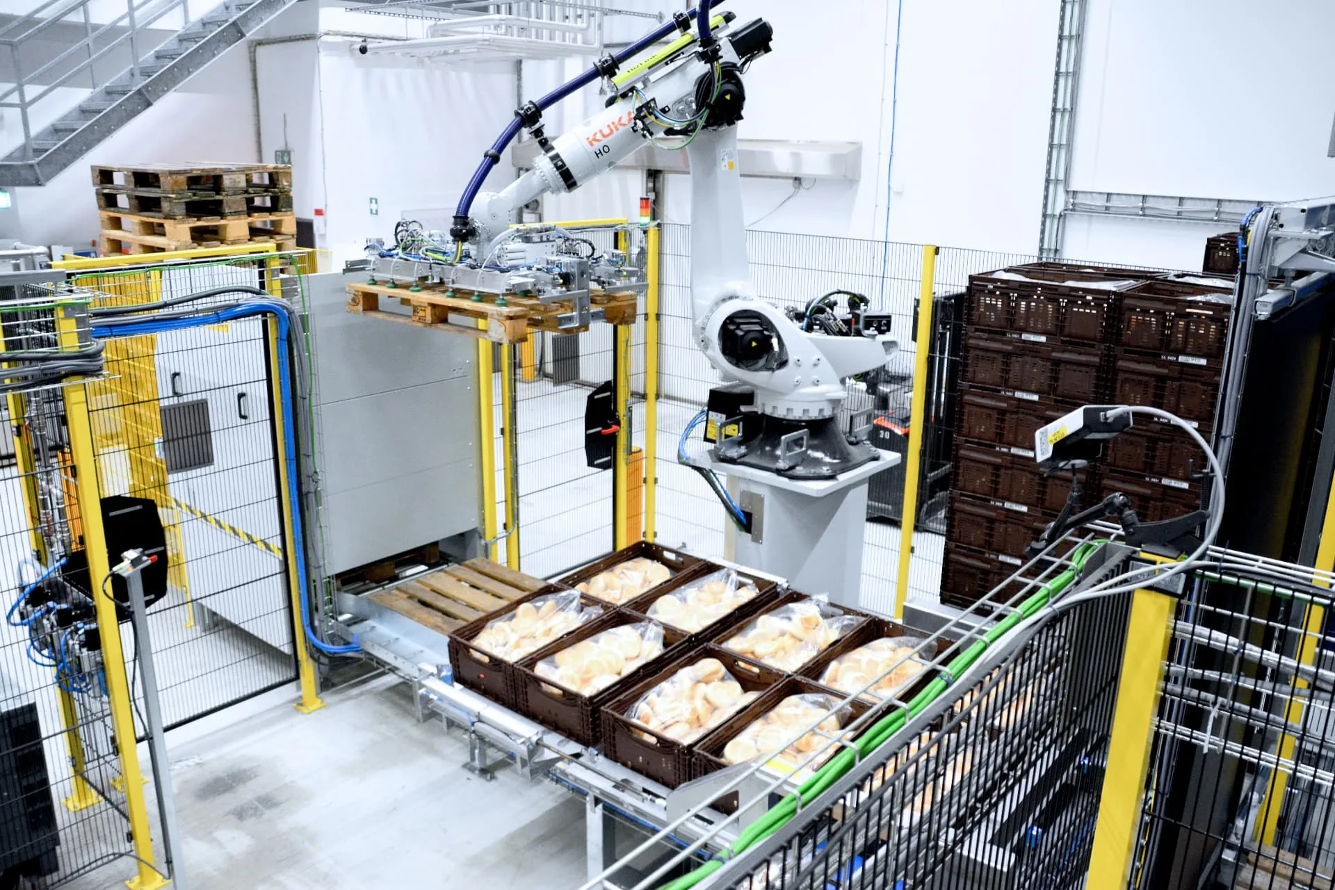 KUKA-Roboter setzt Leerpalette unter gefüllte Backwarenkisten