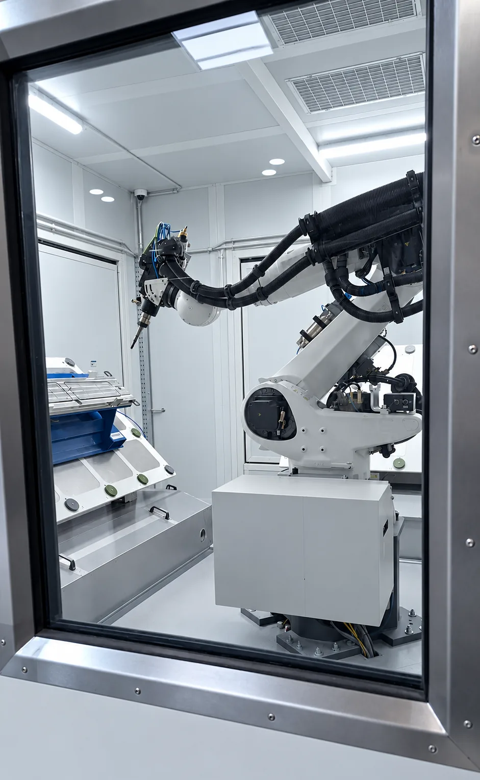 Fräs-Bohr-Roboter hinter dem Sichtfenster der Schutzeinhausung